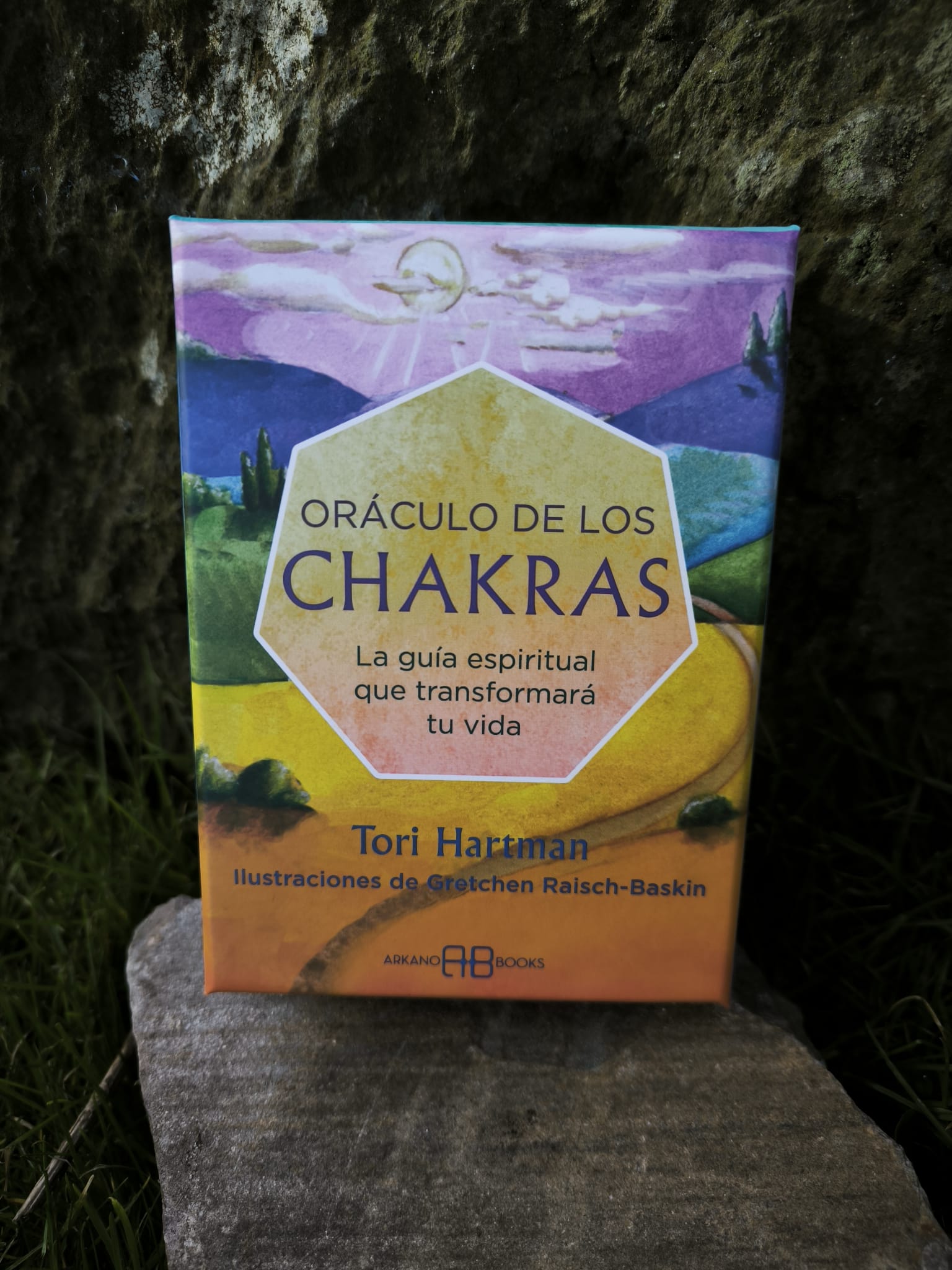Caja del Oráculo de los Chakras de Tori Hartman con paisaje ilustrado en tonos amarillos y violetas.